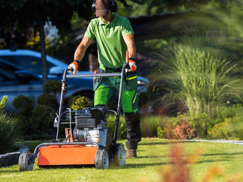 Landscaper operating a lawn aerator on a residential property